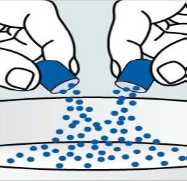 Due mani stringono cilindri blu da cui cadono numerose palline blu su una superficie bianca sottostante