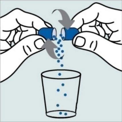 Due mani aprono una capsula blu e bianca con contenuto granulare che cade in un bicchiere trasparente