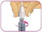 Mano che tiene un contagocce sopra un flacone di vetro trasparente con tappo rosa e misurazioni laterali