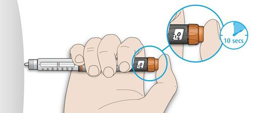 Mano che tiene un dispositivo per iniezione con ago visibile e indicatore di tempo impostato a 10 secondi in un cerchio di ingrandimento
