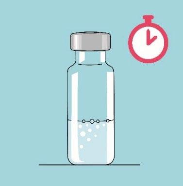 Fiala di vetro trasparente con liquido chiaro e bollicine accanto a un timer rosso con ago che indica un tempo specifico