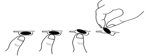 Mano che stringe una capsula oblunga e la rilascia gradualmente su una superficie piana con altre capsule