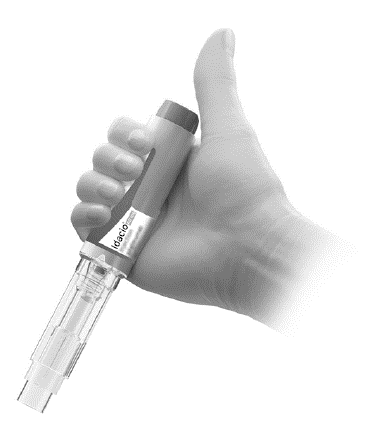Mano che stringe un dispositivo autoiniettante Idacio con cartuccia trasparente e ago visibile pronto per l