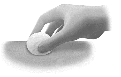 Mano che preme un batuffolo di cotone su una superficie chiara con ombreggiature sottili