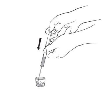 Mano che tiene una siringa con ago sopra un contenitore di vetro trasparente con liquido all