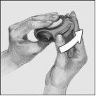 Hands holding a circular medical device with a white arrow indicating its use or direction