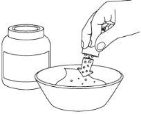 Hand opening a sachet over a container with water, the sachet contains a white powder that is poured into the liquid